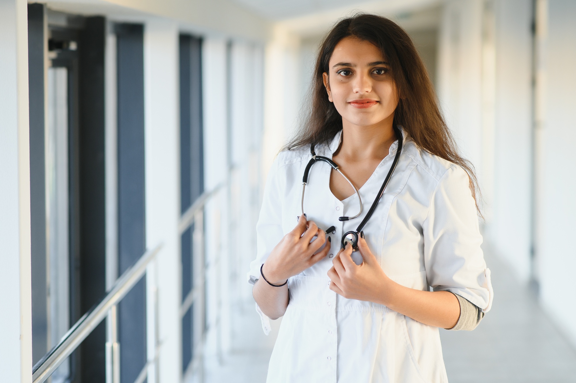An Indian Asian female medical doctor in a hospital office with stethoscope.